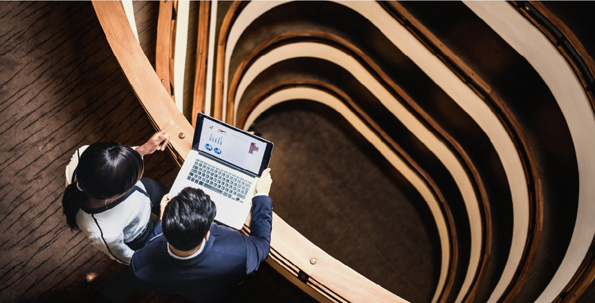 two people with a laptop standing on a balcony overlooking a staircase image