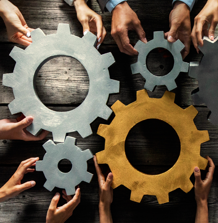 Image of different gears being put together with hands 