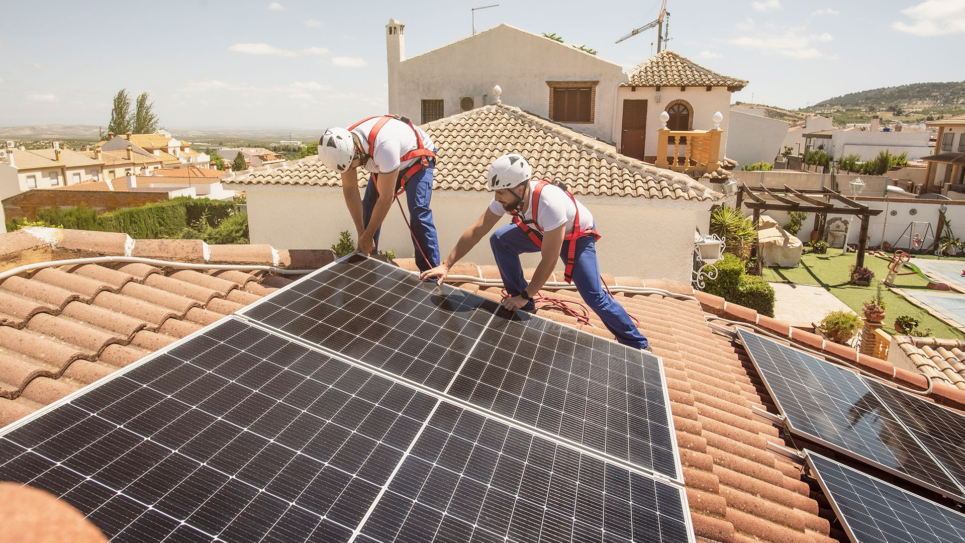 Workers installing solar panels on the roof of a home