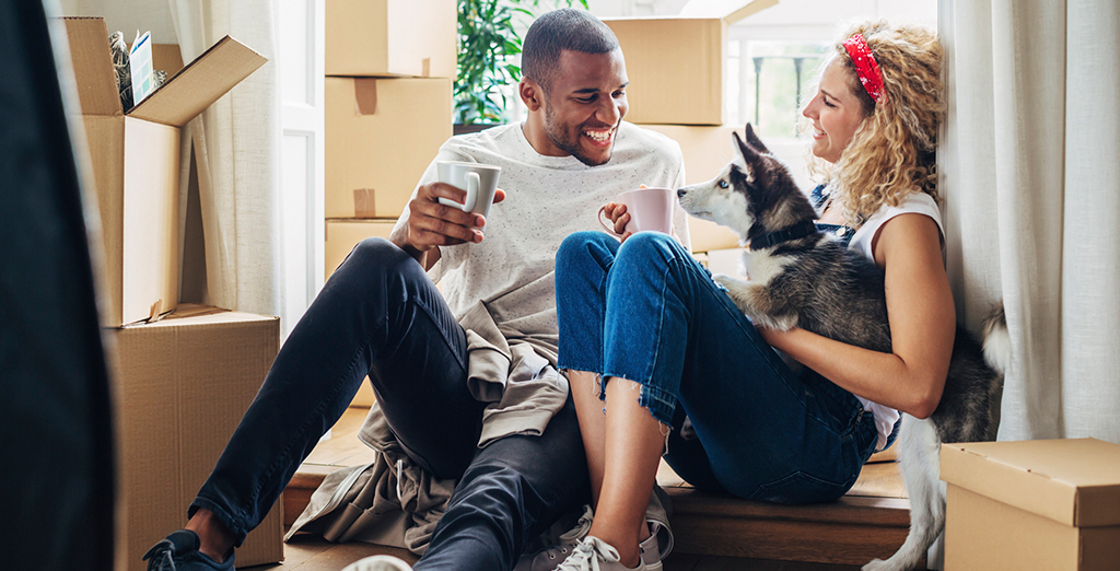 Young couple sitting in their new home surrounded by boxes