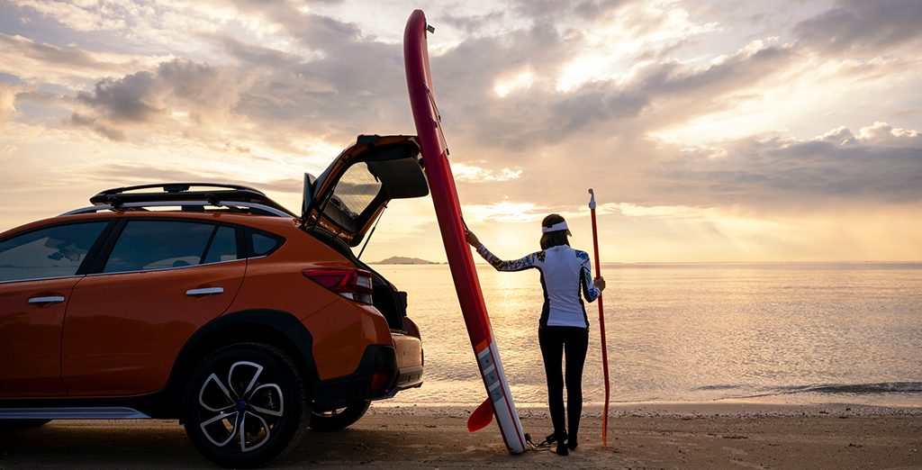 Young professional unloading her car before surfing