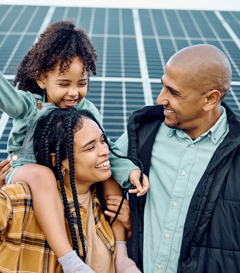 happy family standing in front of solar pannels
