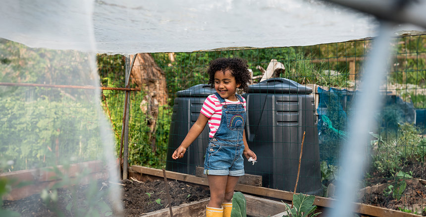 girl standing in garden with water spraying