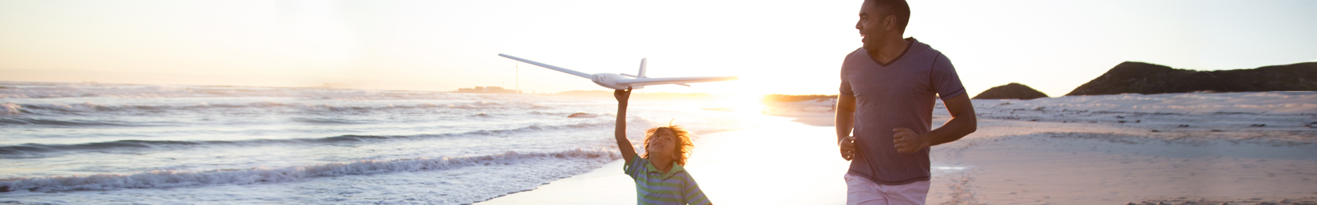 Travel | Father and son play on a beach with an aeroplane