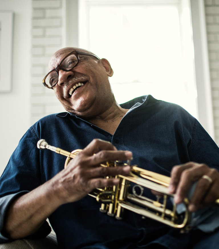 man laughing while holding a trumpet