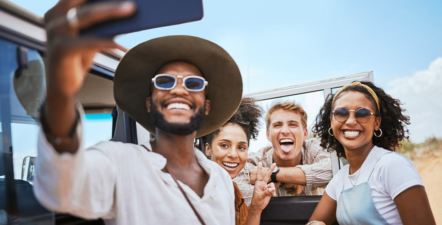 Group of young professionals taking a photo by the beach next to their vehicle