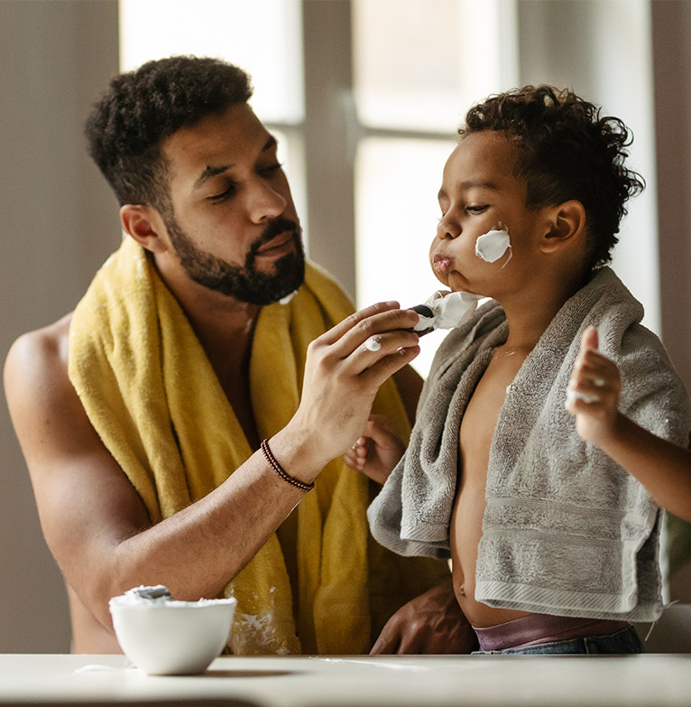 Father and son putting shaving foam on face