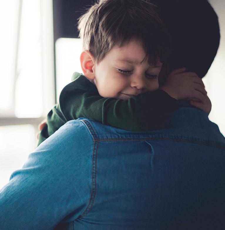 Young boy cuddling his father