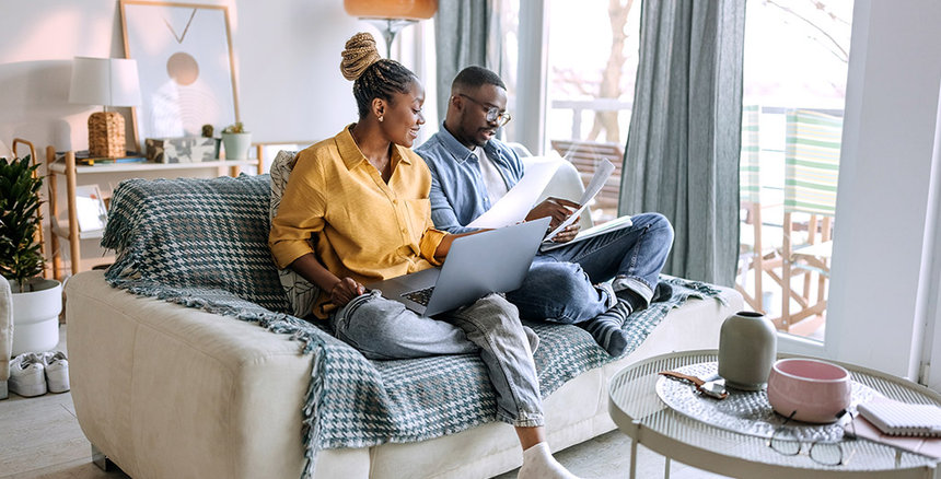Young professionals couple sitting on sofa looking at life insurance