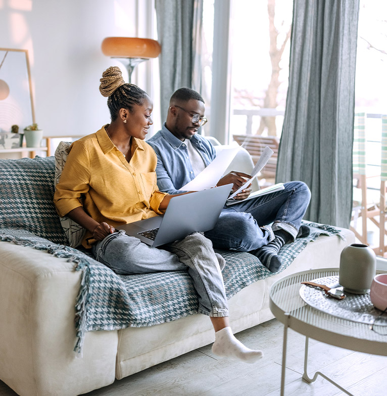 Young professionals couple sitting on sofa looking at life insurance