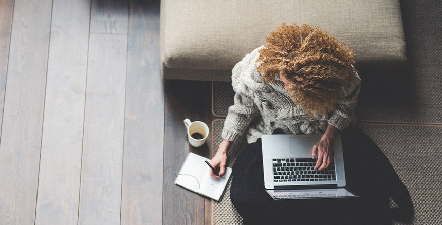 Female working on laptop sitting on the floor at home
