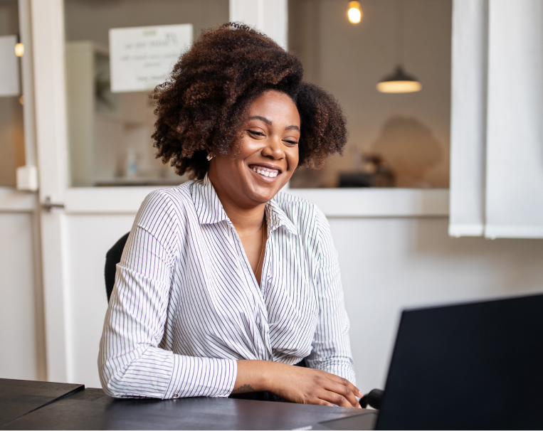 lady smiling and working on ger laptop in an office