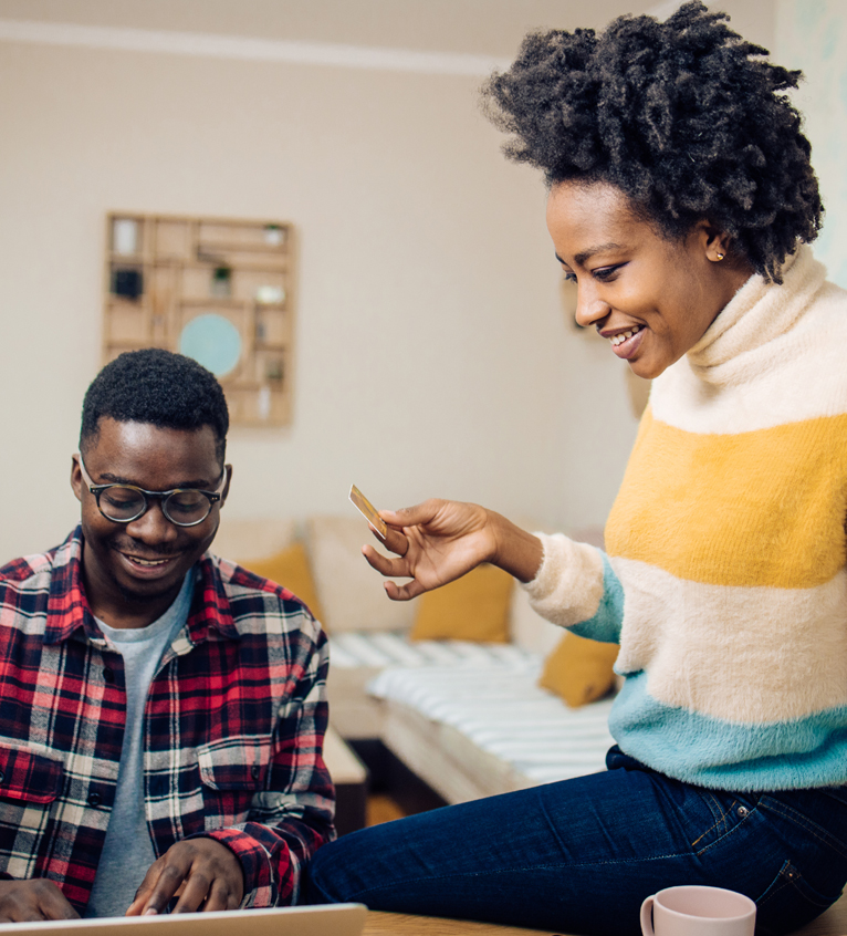 Two individuals engaging with a laptop and a credit card, possibly involved in an online transaction for a first-time home buyer.