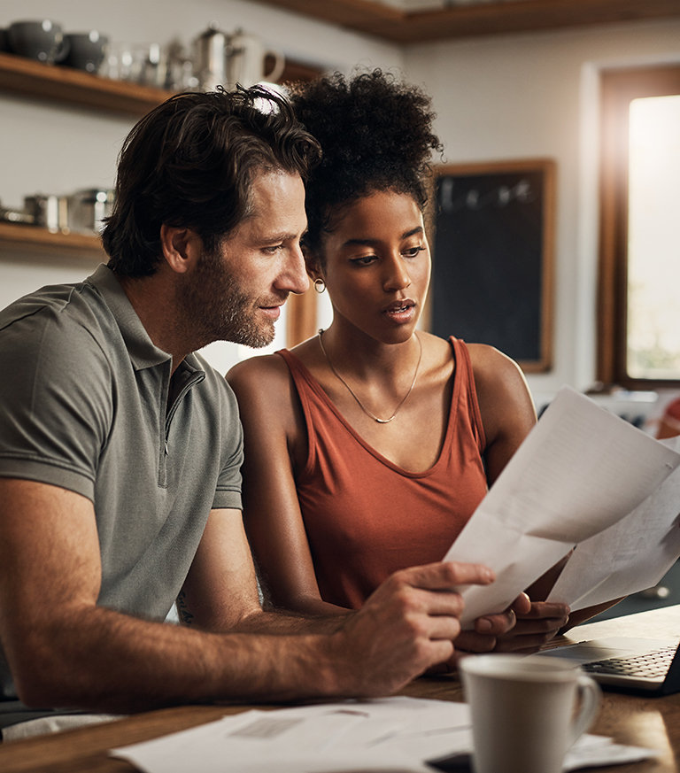 A man and a woman reviewing short term insurance documents together at a kitchen table.