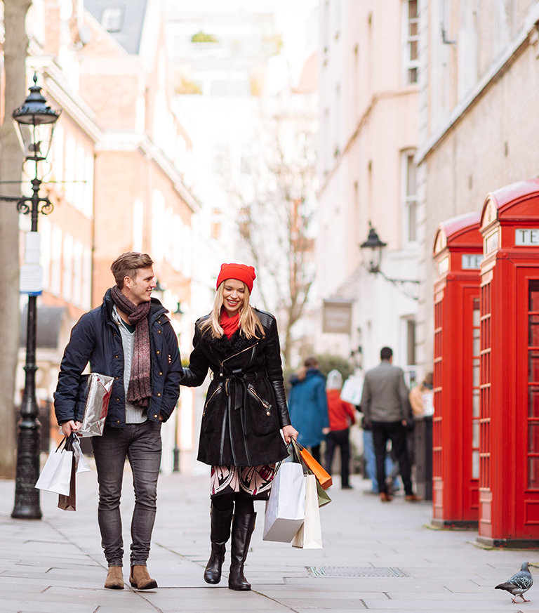 A man and a woman holding shopping bags using their international transactional account
