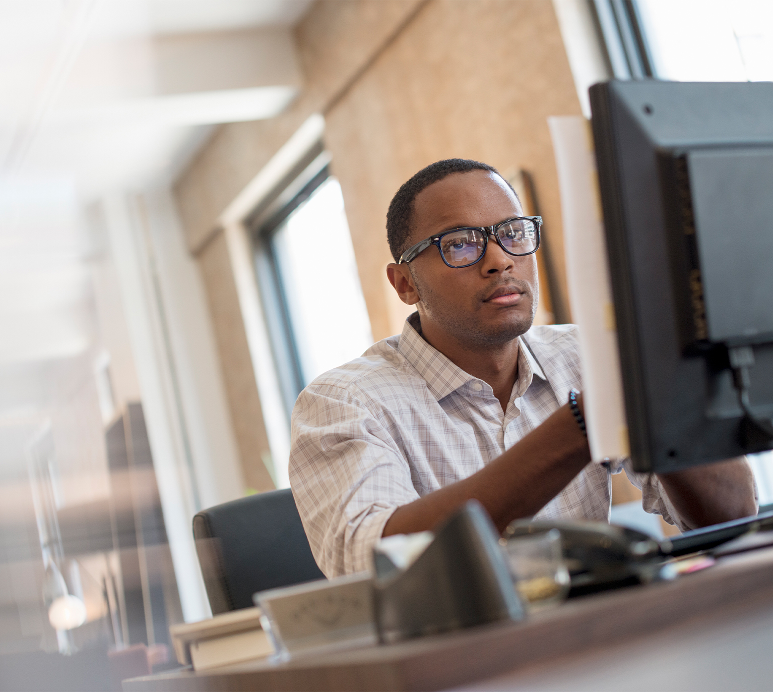 A young man seated at a desk using a computer