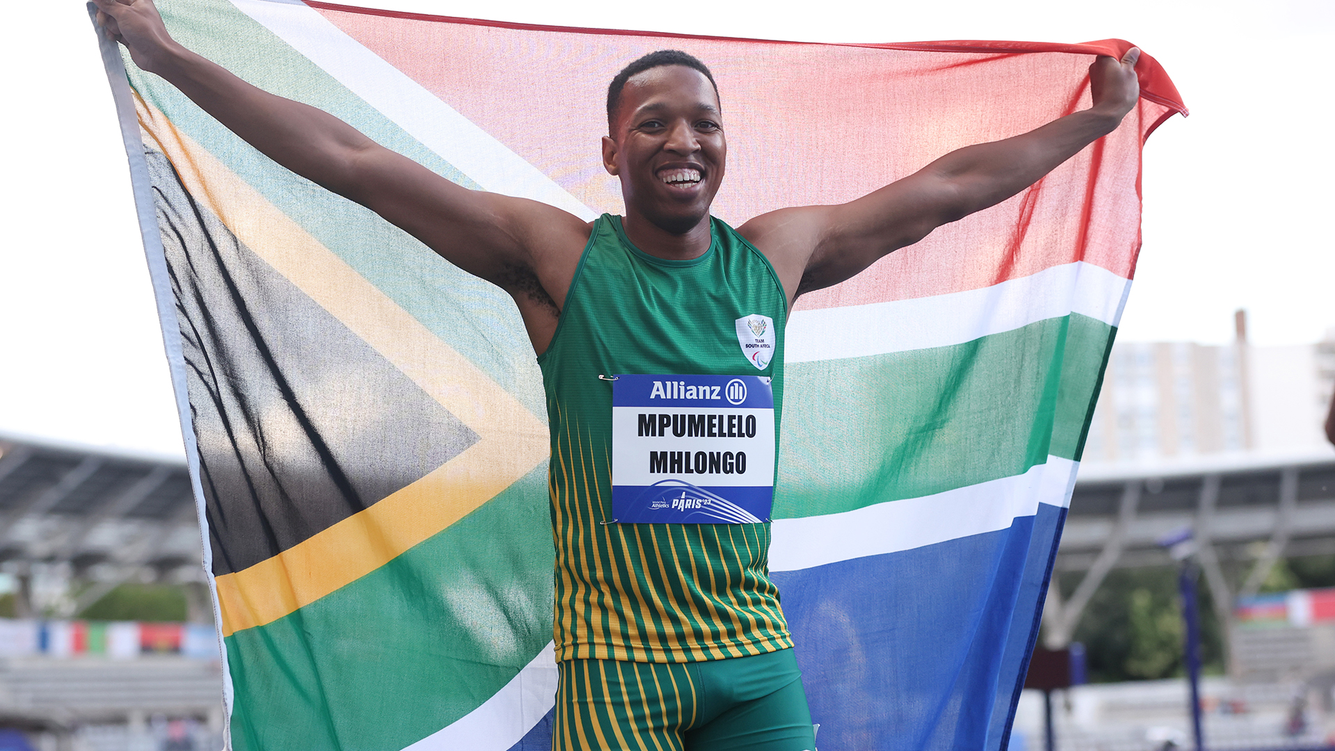 An elated Mpumi , SA flag aloft, having just won gold for the Men's 100m T44