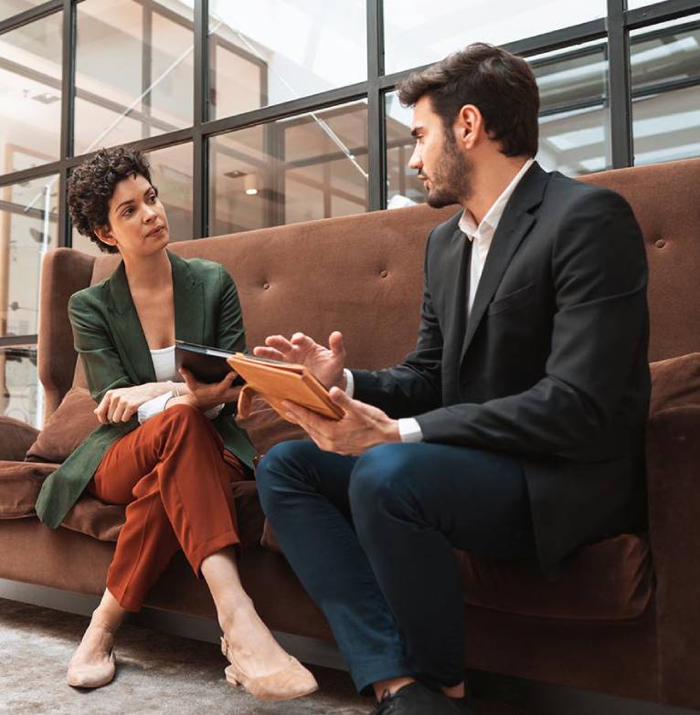Two business people discuss plans on an iPad in an office