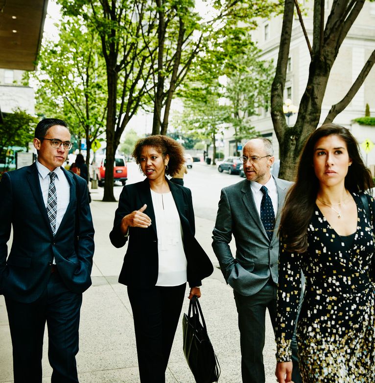 A team of business individuals walking along a street talking together