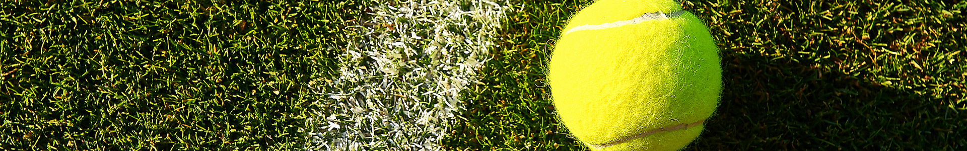 Tennis ball next to baseline on tennis court