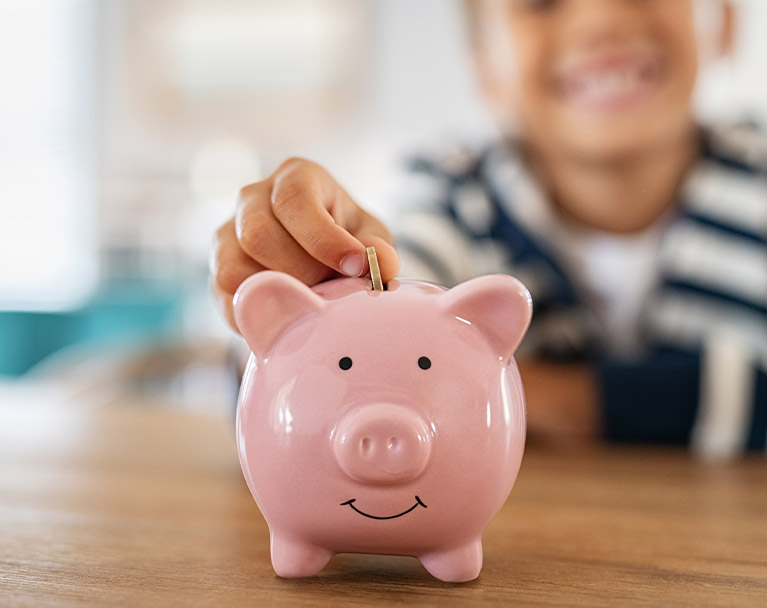 Young child putting coin into piggy bank