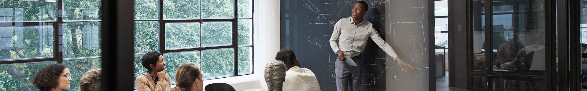 Team discussing in a meeting room with a male at the white board