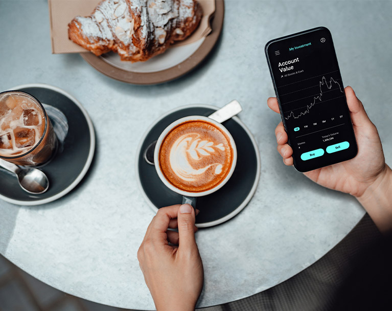 Person checking stocks on an app while drinking a coffee