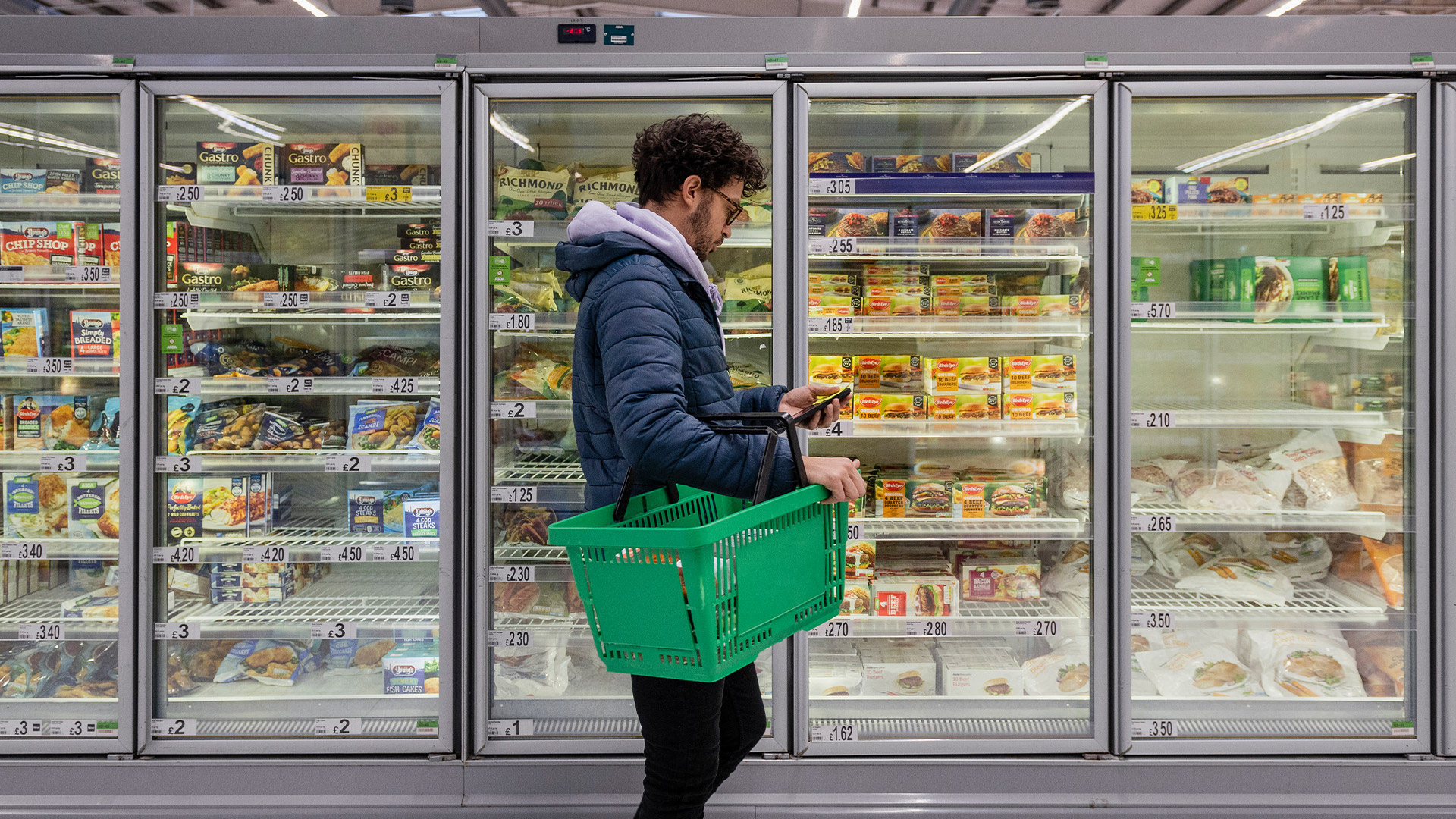 Male shopper in a supermarket checking his phone