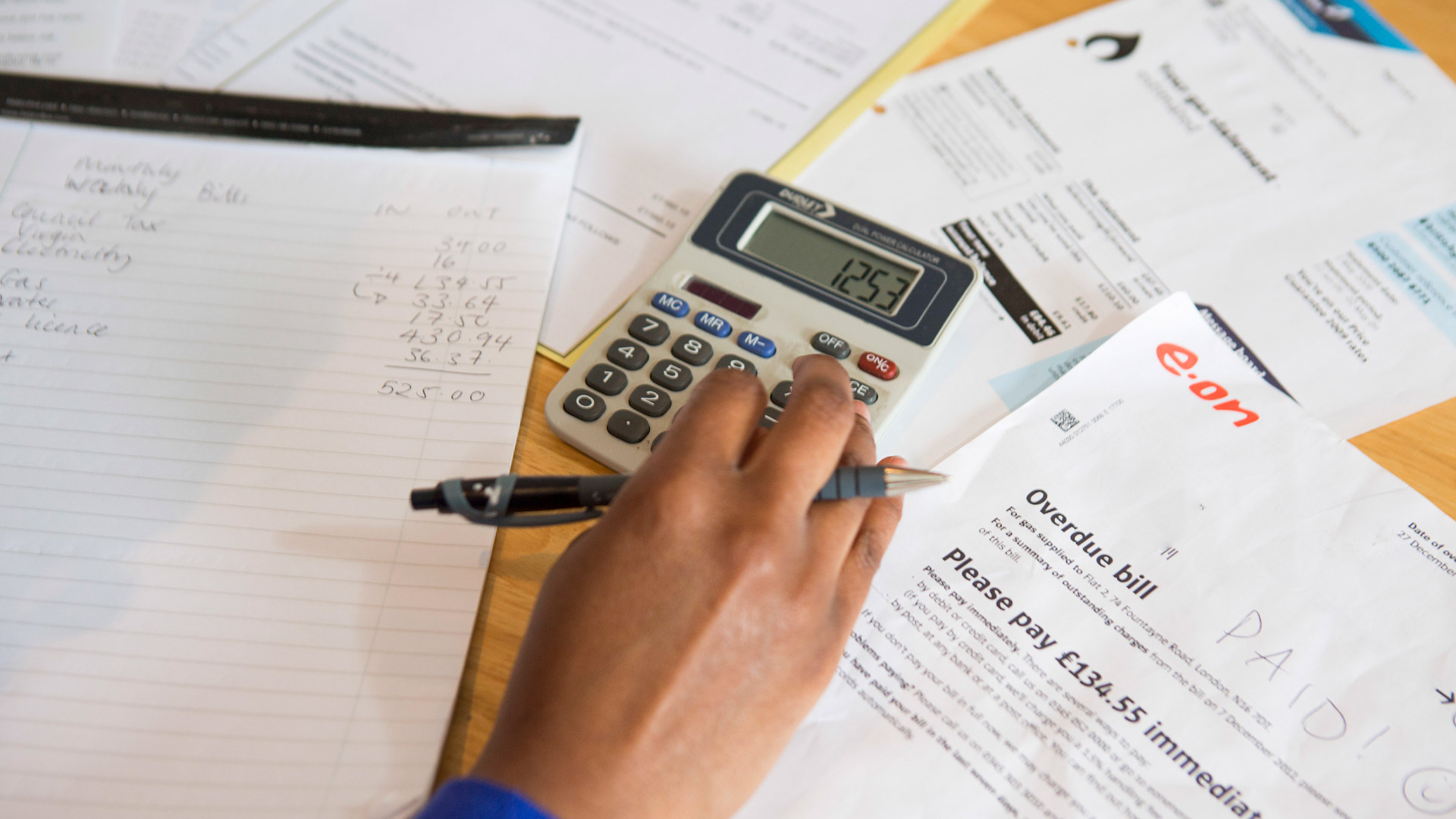 person using calculator and working through bills