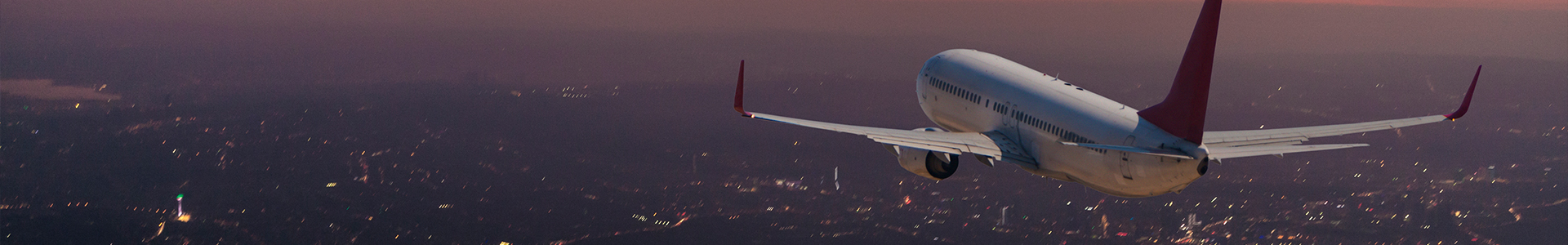 A plane flying in the evening with the sun setting