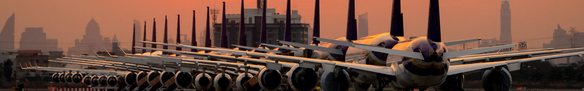 Row of aeroplanes at airport with sunset in background