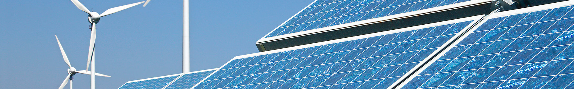 Close-up of solar panels with wind turbines in background