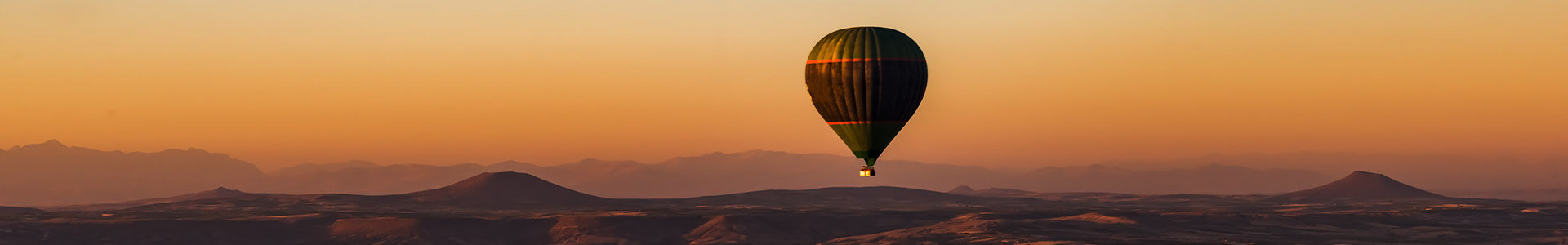 Hot air balloon over desert at sunset