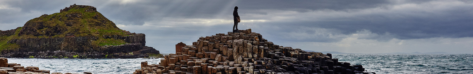 Person standing on top of a pile of rocks in the sea
