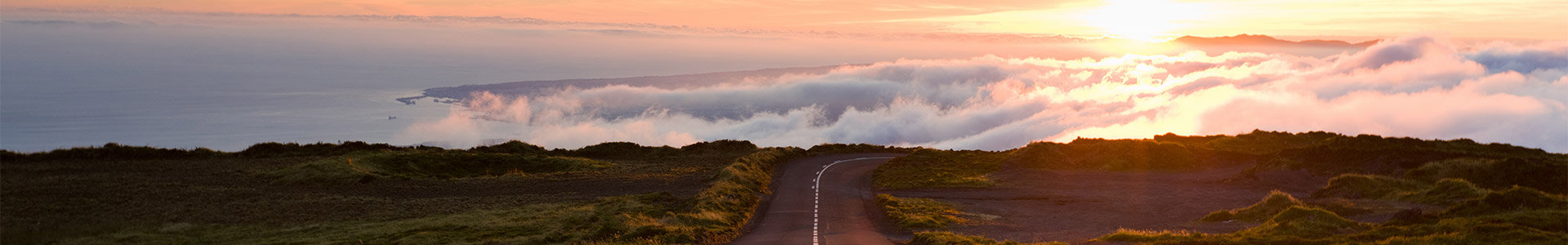 Long straight road with sunset appearing at the end
