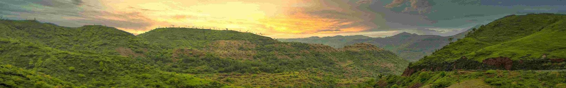 Vast green hills and land with sun setting behind