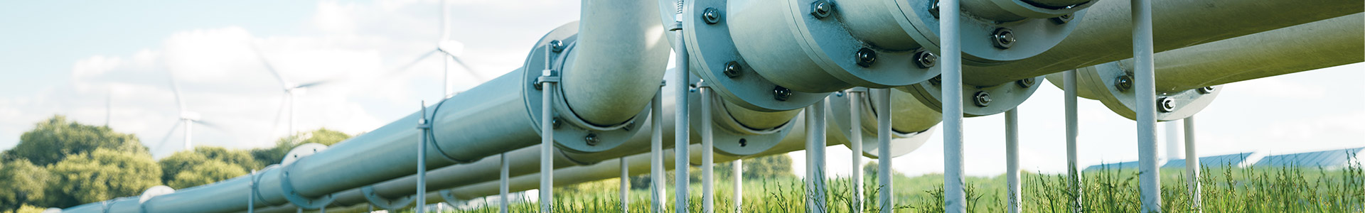 Pipes with wind turbines and solar panels in the background