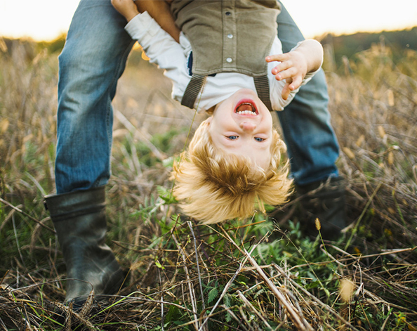 Young boy swinging under his father