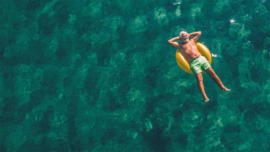 Investor looking back while relaxing on rubber ring in the sea