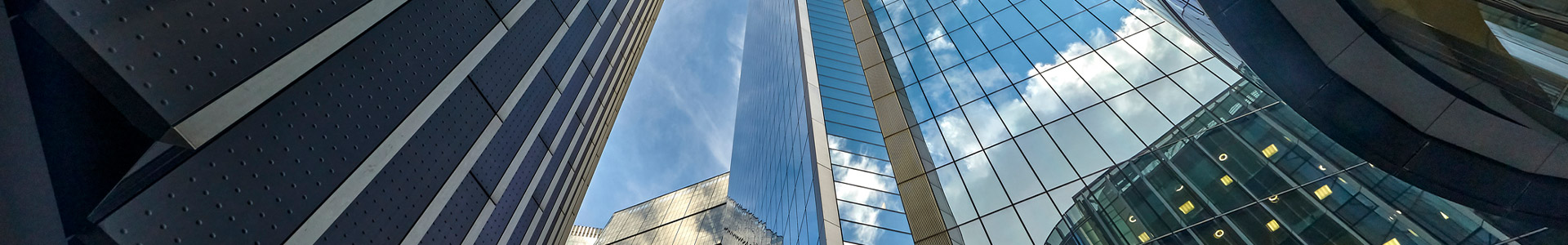 Looking upwards at multiple glass fronted sky scrapper buildings