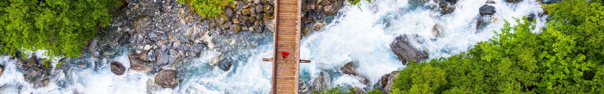person walking over a wooden bridge across a river