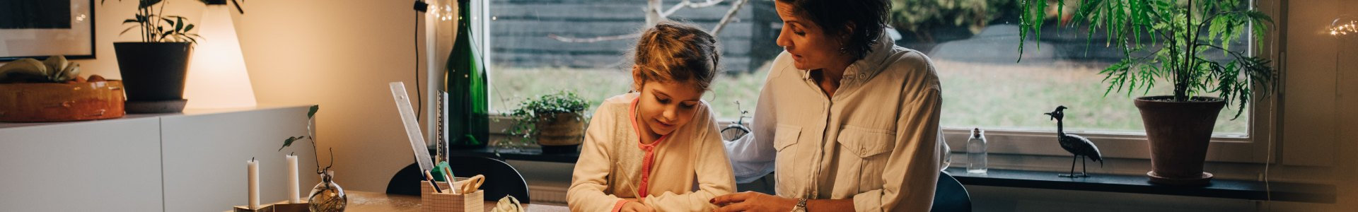 Mother helps her daughter with homework at kitchen table