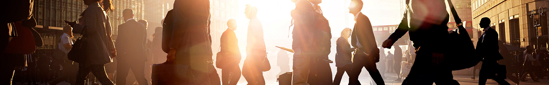 People walking across a road to work with sunshine in the background