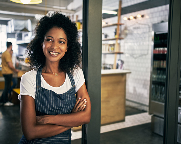 Female standing outside her shop smiling