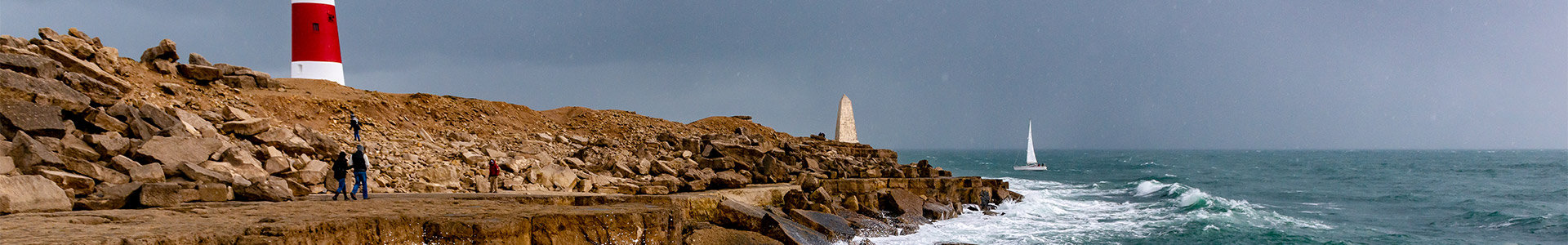 Lighthouse on the edge of a cliff with waves crashing into the rocks