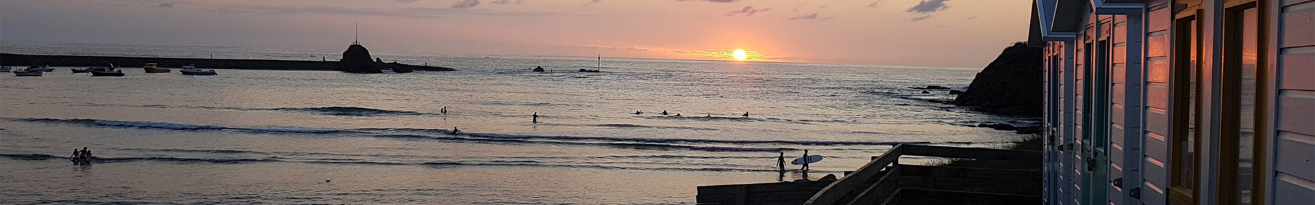 Beach huts by side of the beach at sunset