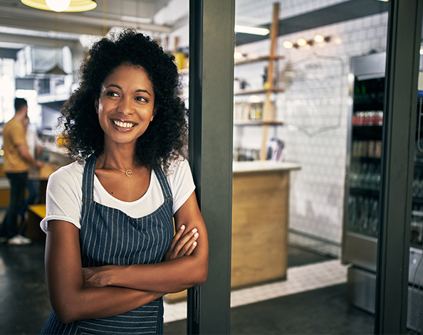 Female standing outside her shop smiling