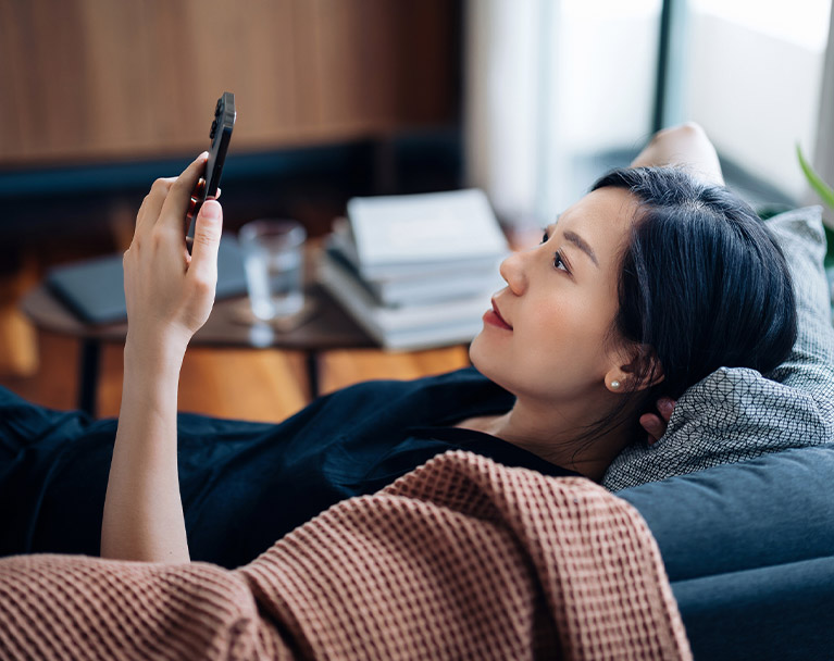 Female lying on sofa viewing mobile phone