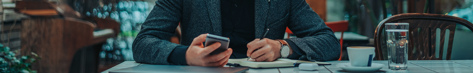 Male checking his finance app on his phone and making notes