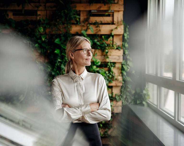 Business woman looking out of a window in an office